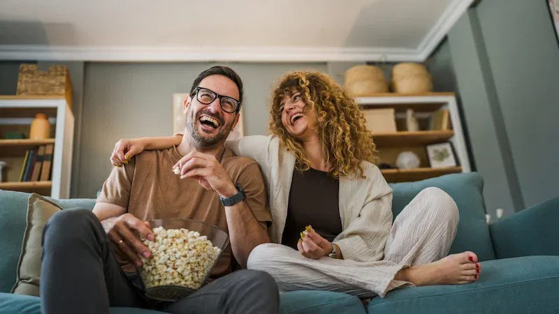 a couple watching tv and eating popcorn